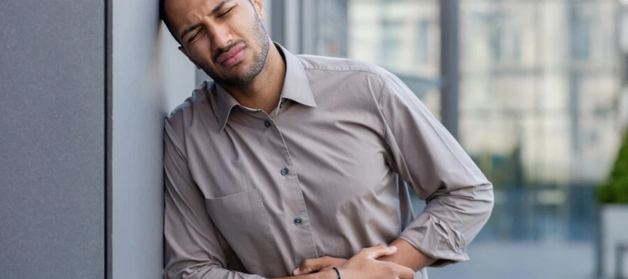 Imagem do post homem no trabalho com as mãos na barriga sentindo dor