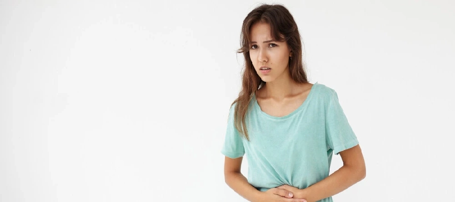 Imagem do post mulher de camiseta verde sentindo a dor da cólica estomacal