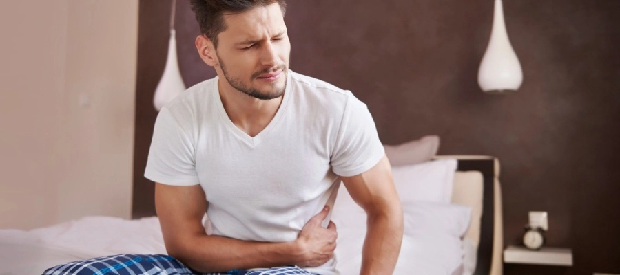 Imagem do post homem de camisa branca com dor na barriga