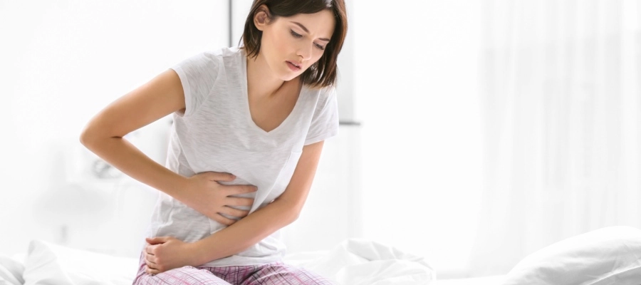 Imagem do post mulher branca com dor de estômago na cama