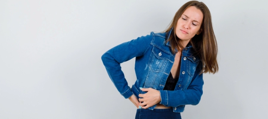 uma mulher em uma jaqueta jeans com dor lombar