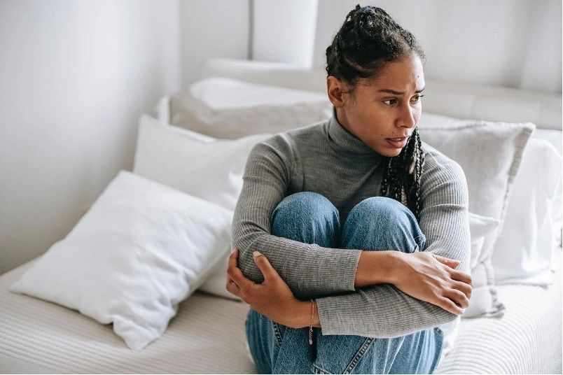 Imagem do post uma mulher sentada em uma cama com os braços cruzados