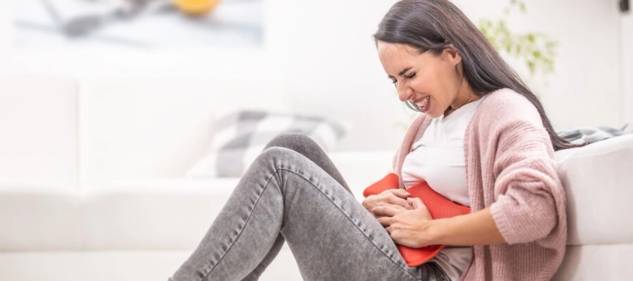 Imagem do post Mulher com dor no estômago segurando uma bolsa térmica na barriga
