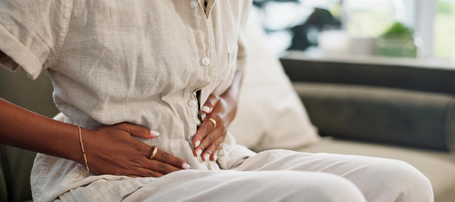 mulher sentada com as mãos na barriga pode ser norovirus