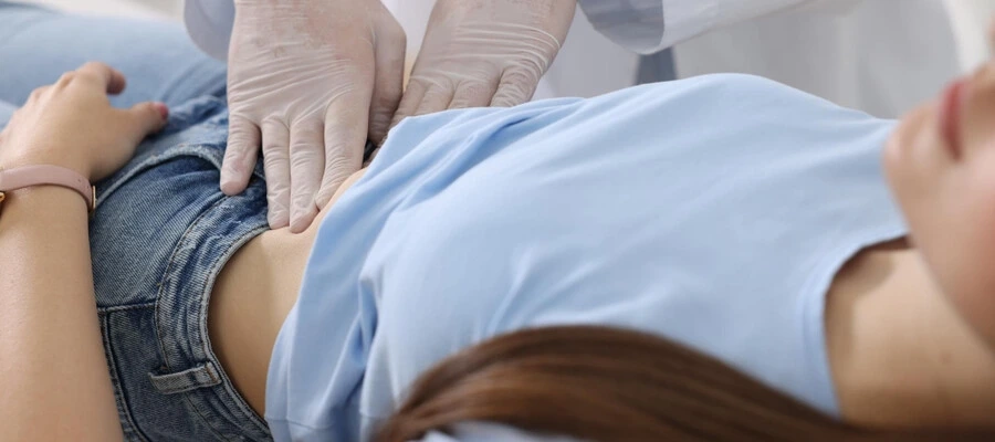 Imagem do post médico examinando a região do abdômen de paciente com dor