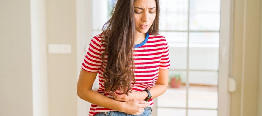 Imagem do post uma mulher em uma camisa listrada vermelha e branca com dor na barriga