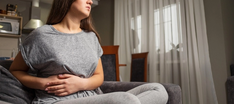 Imagem do post jovem no sofá com dor na lateral da barriga