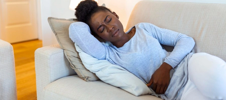 Imagem do post mulher negra deitada no sofá com dor