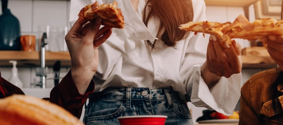 Imagem do post pessoas comendo pizza em uma cozinha