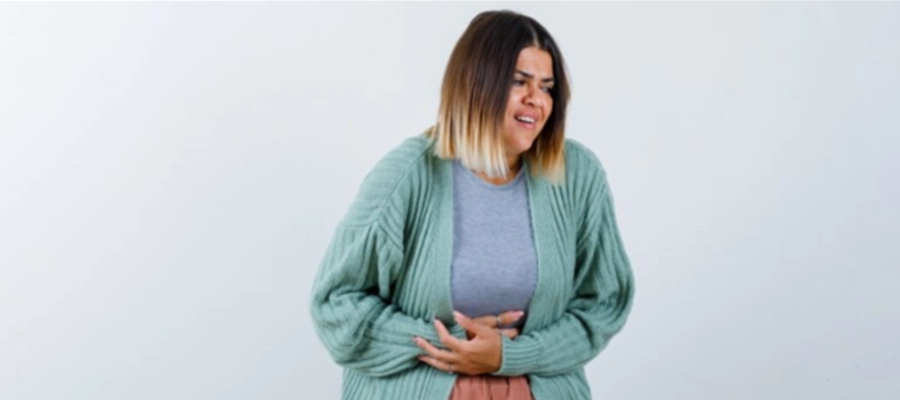 Imagem do post uma mulher em um suéter cardigan verde com as mãos na barriga