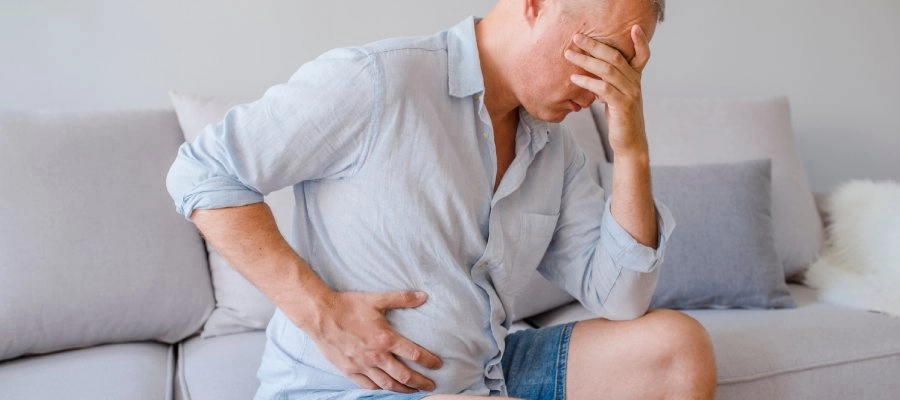 Imagem do post homem senta no sofá com dor na lateral da barriga