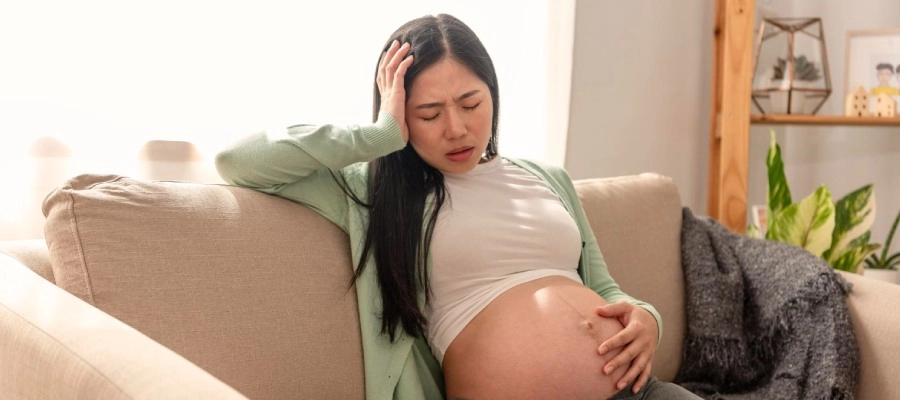 Imagem do post uma menina grávida sentada em um sofá com as mãos em sua barriga